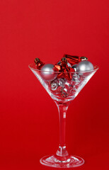 Christmas silver and red toys in a glass goblet on a red background
