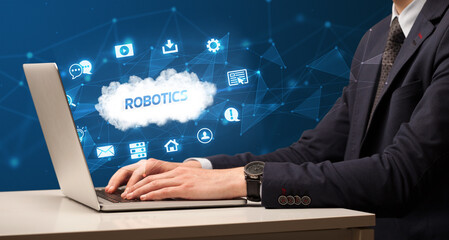 Businessman working on laptop with ROBOTICS inscription, modern technology concept