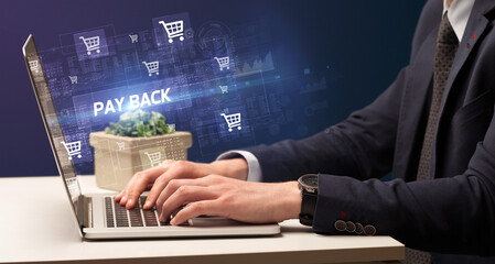 Businessman working on laptop with PAY BACK inscription, online shopping concept