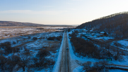 Snow-capped hills and road at sunset background photographed from drone