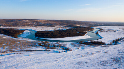 Snowy forest and river photographed from drone