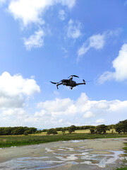Drone in flight against the background of sky and grass