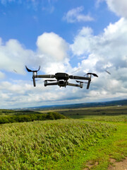 Drone in flight against the background of sky and grass