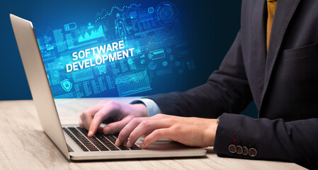 Businessman working on laptop with SOFTWARE DEVELOPMENT inscription, cyber technology concept