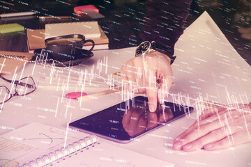 Double exposure of man's hands holding and using a digital device and forex graph drawing. Financial market concept.