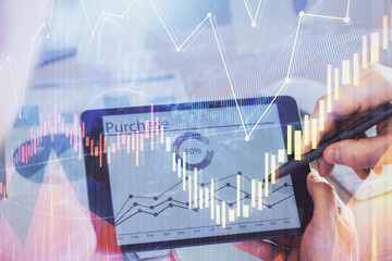 Double exposure of man's hands holding and using a phone and financial chart drawing. Market analysis concept.