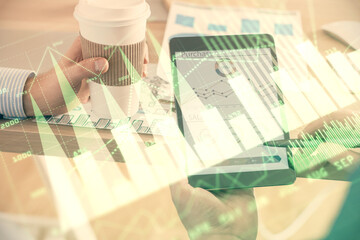 Double exposure of man's hands holding and using a phone and financial chart drawing. Market analysis concept.