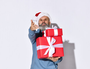 Winter fashion and sales. Smiling senior bearded man holding a bunch of gift boxes and holding out his hands to you, offering to buy or give presents for Christmas.