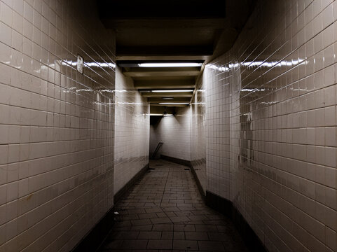 Dark Hallway With Reflective White Tiles And Bright Lights To Subway Trains In New York City