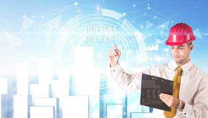 Handsome businessman with helmet drawing ONLINE SURVEY inscription, contruction business concept