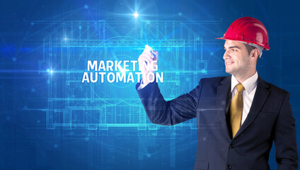 Handsome architect with helmet drawing MARKETING AUTOMATION inscription, new technology concept