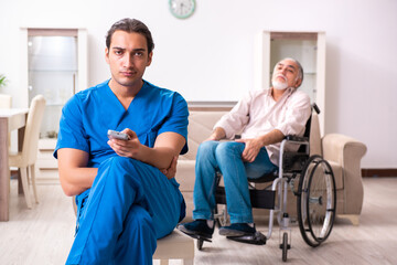 Obraz premium Old man in wheel-chair and young bad caregiver indoors