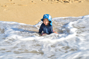 Fototapeta na wymiar 沖縄の波打ち際で遊ぶ男の子