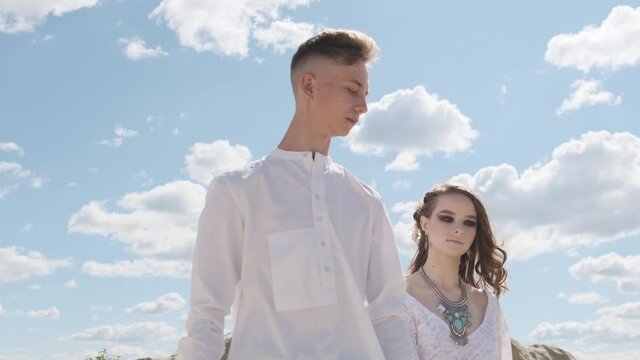 A guy and a girl walk together on a sandy quarry dressed in boho style