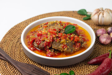 Dendeng Balado, Indonesian traditional beef cuisine from Padang, West Sumatra with slices beef cooked with some spices and a lot of chilies. served on ceramic plate and isolated white background.   