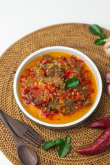Dendeng Balado, Indonesian traditional beef cuisine from Padang, West Sumatra with slices beef cooked with some spices and a lot of chilies. served on ceramic plate and isolated white background.   