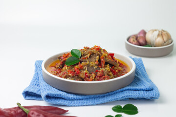 Dendeng Balado, Indonesian traditional beef cuisine from Padang, West Sumatra with slices beef cooked with some spices and a lot of chilies. Served on ceramic plate and isolated white background.   