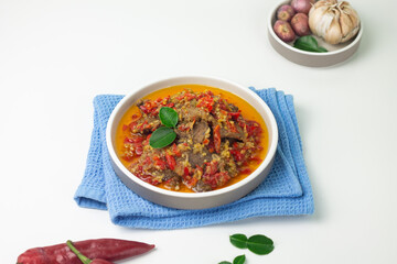 Dendeng Balado, Indonesian traditional beef cuisine from Padang, West Sumatra with slices beef cooked with some spices and a lot of chilies. Served on ceramic plate and isolated white background.   