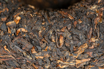 Chinese Cooked Pu Er tea in the form of a nest in a paper wrapper, macro image. 