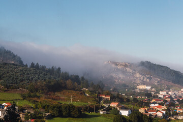 Fototapeta na wymiar mist coming down the mountain and covering the houses