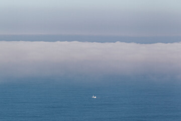 aerial view of fishing boat sailing in the sea entering a fog bank