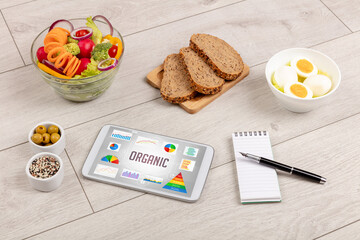 Organic food and tablet pc showing ORGANIC inscription, healthy nutrition composition