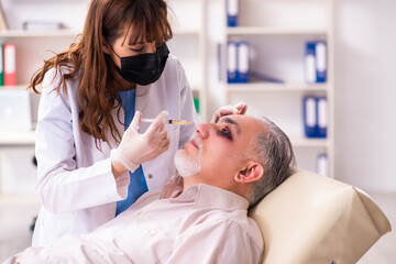 Obraz premium Old man visiting young female doctor for plastic surgery