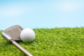 Fotobehang Golf Golf ball with iron are on green grass on blue sky background  © thaninee