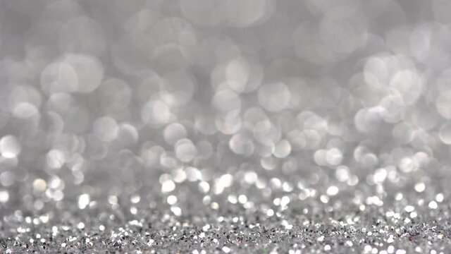 Magic silver background for Christmas, new year party. Shiny glitter surface is moving. Festive lights and bokeh