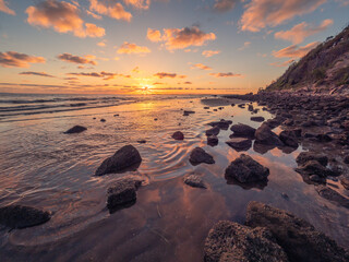 Fototapeta na wymiar Beautiful Seaside Sunrise with Cloud Reflections and Rocks