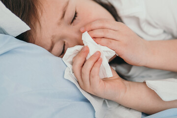 The little girl caught a cold. Children sneeze into a handkerchief. The child is ill and is being treated at home. Seasonal colds in children