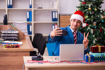 Young male employee celebrating Christmas at workplace