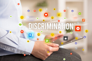 Close up of business person playing multimedia with social media icons and DISCRIMINATION...