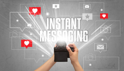 Close-up of a hand taking photos with INSTANT MESSAGING inscription, social media concept