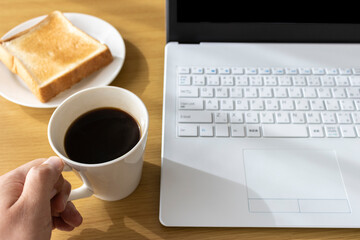 朝食を食べながら、ノートパソコンを使う、イメージ