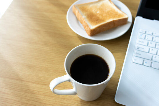 朝食を食べながら、ノートパソコンを使う、イメージ