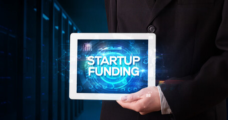 Young business person working on tablet and shows the inscription: STARTUP FUNDING, business concept