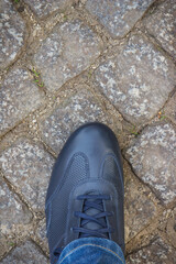 Navy blue leather shoes for men on footpath made of rocks or stones. Male footwear. Copy space for text