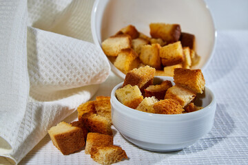 Square toasted pieces of homemade delicious rusk, hardtack, Dryasdust, zwieback in a plate on a white tablecloth.