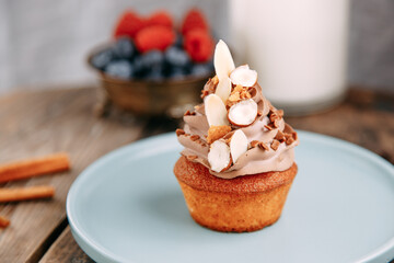 Chocolate dessert with soft milk cream. Tartlet with chocolate chips on a wooden background.