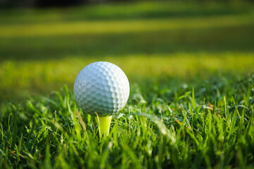Golf ball on tee in beautiful golf course at sunset background