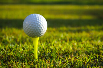 Golf ball on tee in beautiful golf course at sunset background