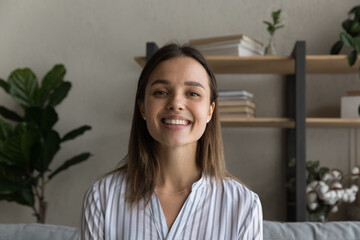 Headshot portrait of smiling young Caucasian woman look at camera speak talk on video call. Profile...