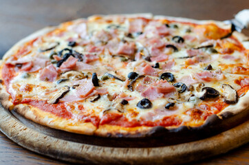 Delicious homemade ham pizza served on wooden plate, selective focus