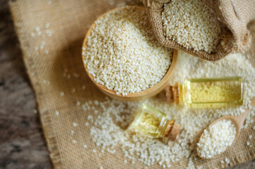 Closed up white sesame seeds in wooden bowl and sack on grunge background and dark tone