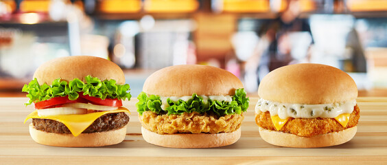 a beef burger chicken burger and fish burger in the wooden table with a background modern of...