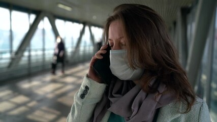 townswoman with face mask from covid-19 infection, is talking by cell phone in pedestrian tunnel - Powered by Adobe