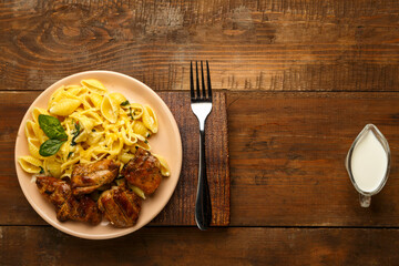 spinach and chicken in a plate on a wooden board next to a fork and a jug of cream.