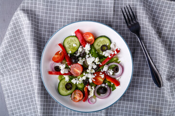 Light plate of Greek salad on a checkered napkin.