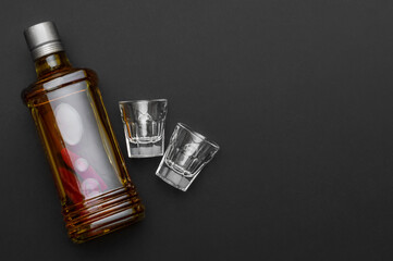Bottle of vodka with small glasses On black background. Space for text.